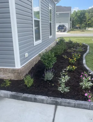 Curved landscaped flower bed along house
